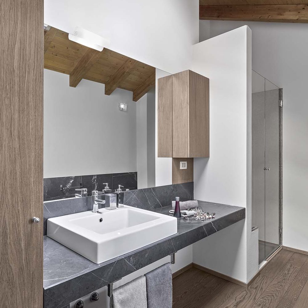 Concorso Riabita 2009               interiors of a modern bathroom in the attic room with wooden  beamed ceiling and the wooden floor,  in the foreground the countertop washbasin on the resting on the marble plane, in the background there is the masonry shower cubicle