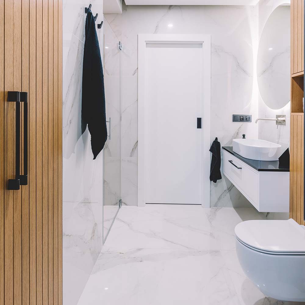 Modern new luxury bathroom. Interior design with marble, wood and stainless steel. Round mirror with led light behind